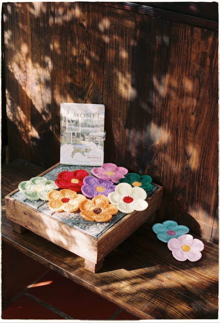 Colorful crochet flowers on wooden surface with a Monet art book